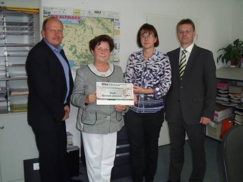 Der Gebietsleiter für Personenversicherungen Erik Lange und ÖSA Geschäftsstellenleiter Guido Klautzsch übergeben einen Scheck über 2.566,- an Bürgermeisterin Verena Schlüsselburg. Anwesend auch die Kämmereiamtsleiterin Sylvia Schwiertz (rechts). scheck-von-der-oesaa